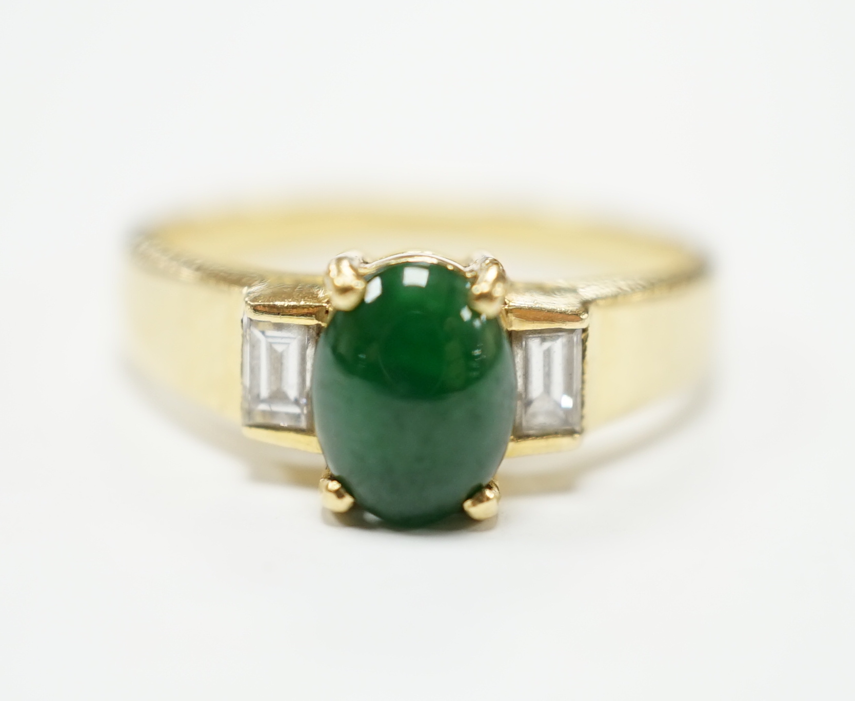 A 750 yellow metal, single stone cabochon jade and two stone baguette cut diamond set ring, size M, gross weight 4.8 grams.